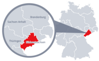 Diese Grafik zeigt eine Karte von Deutschland mit einer detaillierten Ansicht der Region Südwestsachsen. Südwestsachsen ist in Rot hervorgehoben und liegt im östlichen Teil Deutschlands. Ein Lupensymbol vergrößert diesen Bereich, um die Lage genauer darzustellen. 