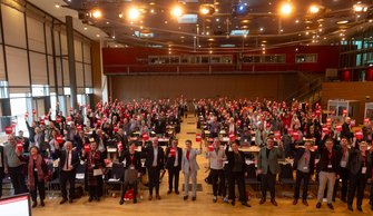 Teilnehmer*innen der DGB-Bezirkskonferenz mit roter Karte gegen Kahlschlag in der Hand..